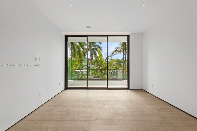 unfurnished room with expansive windows and light hardwood / wood-style floors