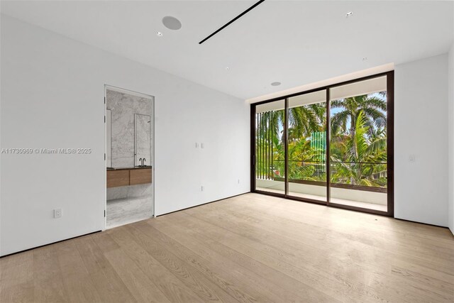 spare room with a wall of windows and light hardwood / wood-style floors