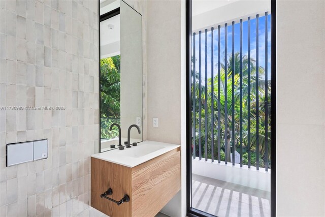 bathroom featuring vanity, a healthy amount of sunlight, and tile walls