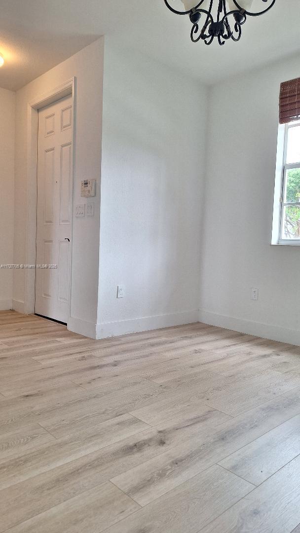 spare room featuring an inviting chandelier and light hardwood / wood-style flooring