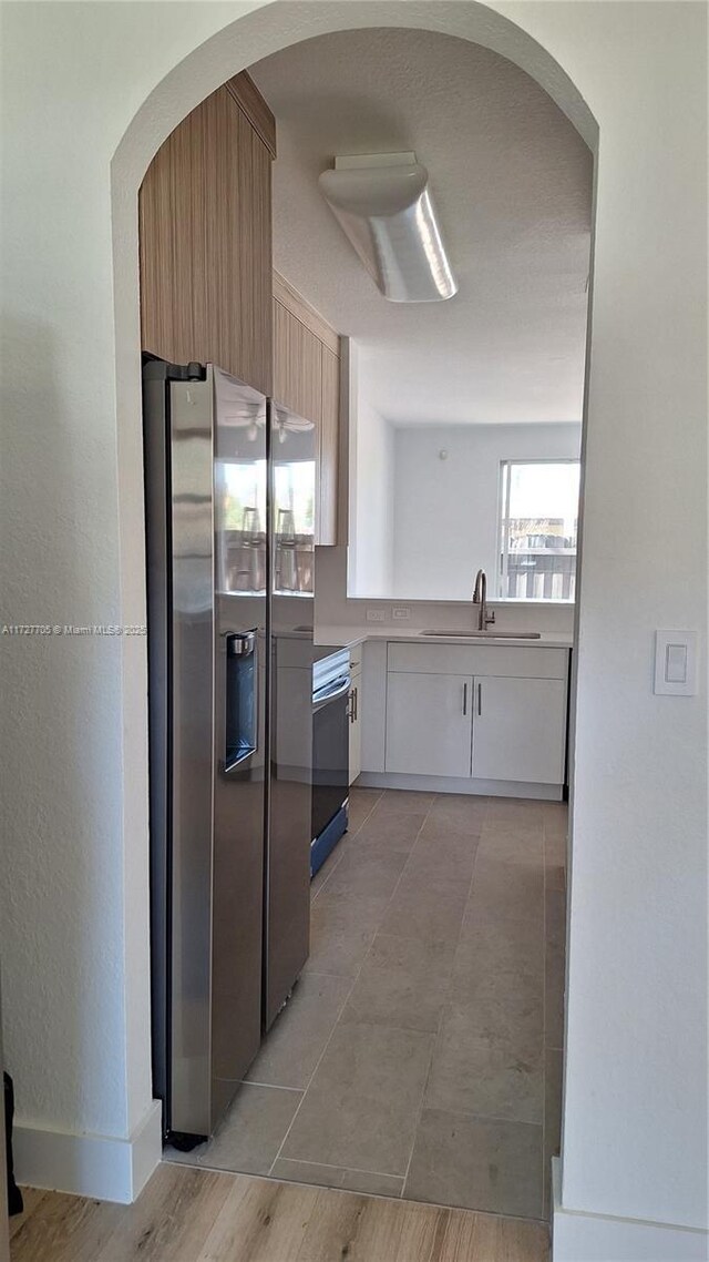 kitchen featuring stainless steel fridge with ice dispenser, sink, white cabinets, and range