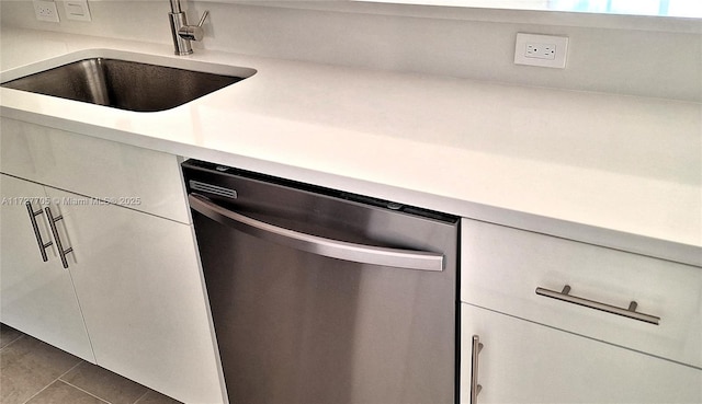 kitchen featuring dishwasher, sink, and dark tile patterned flooring