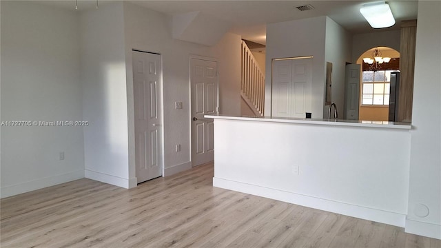 kitchen featuring a notable chandelier, stainless steel fridge, light wood-type flooring, and kitchen peninsula