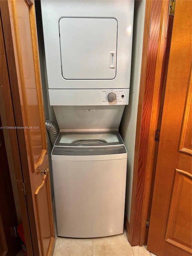 laundry room with stacked washer and dryer and light tile patterned floors