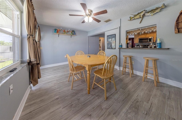 dining area featuring ceiling fan, a textured ceiling, and light hardwood / wood-style flooring