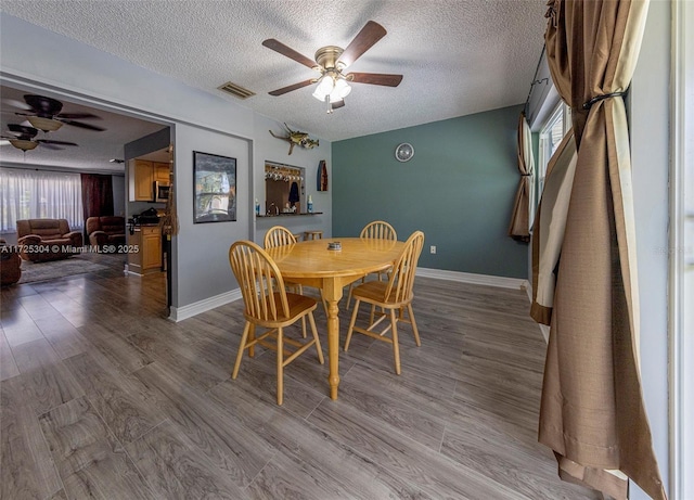 dining space with hardwood / wood-style flooring, a textured ceiling, and ceiling fan