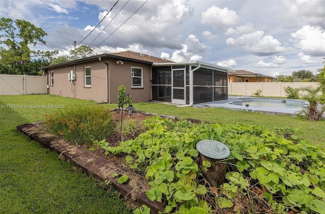 rear view of property featuring a yard, a fenced in pool, and a sunroom