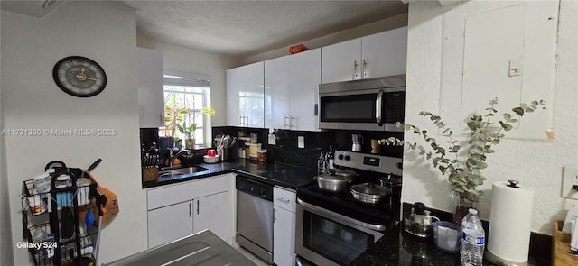 kitchen with tasteful backsplash, white cabinetry, sink, stainless steel appliances, and a textured ceiling