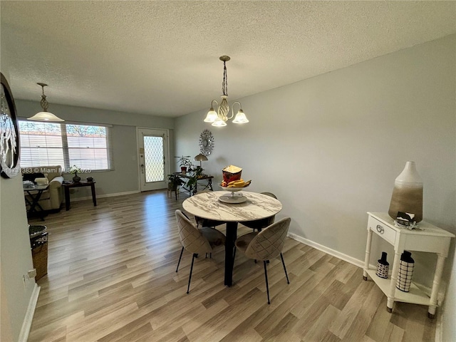 dining space featuring an inviting chandelier, a textured ceiling, and light wood-type flooring