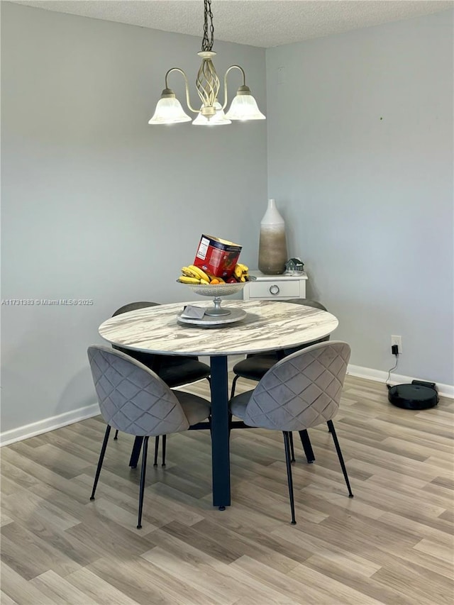 dining space with an inviting chandelier, light hardwood / wood-style floors, and a textured ceiling