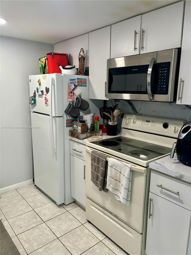 kitchen featuring light stone counters, white appliances, white cabinets, and light tile patterned flooring