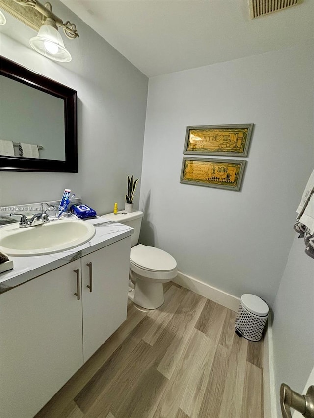 bathroom with hardwood / wood-style flooring, vanity, and toilet