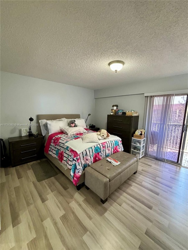 bedroom featuring light wood-type flooring, a textured ceiling, and access to outside