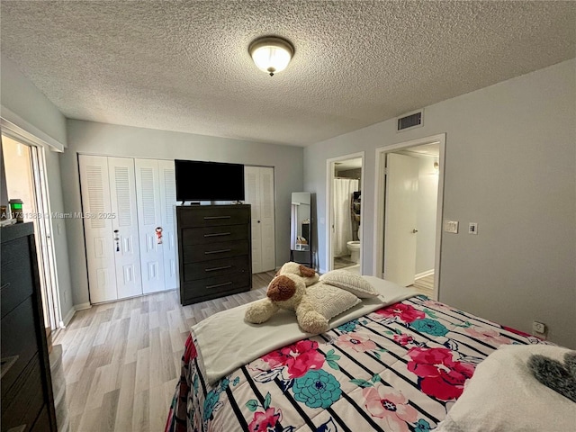 bedroom with ensuite bathroom, a textured ceiling, and light hardwood / wood-style flooring