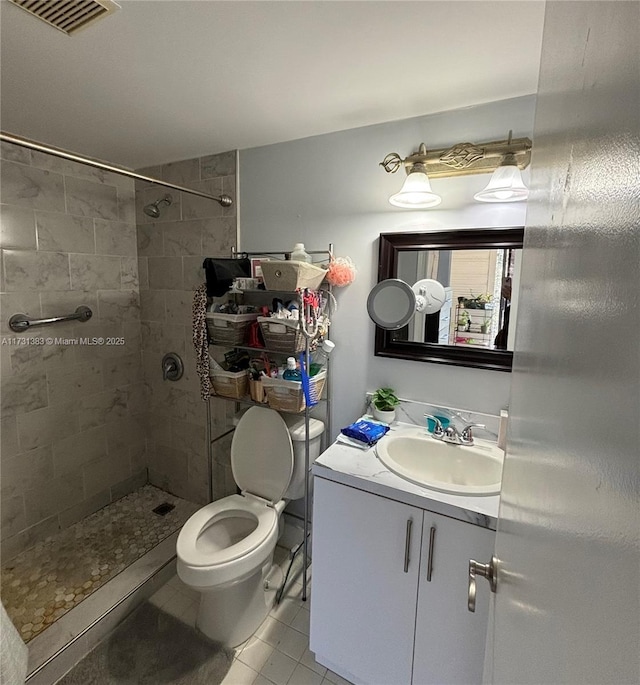 bathroom featuring tile patterned floors, toilet, vanity, and a tile shower