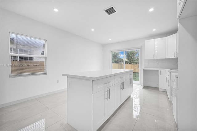 kitchen with a center island, light tile patterned floors, decorative backsplash, and white cabinets