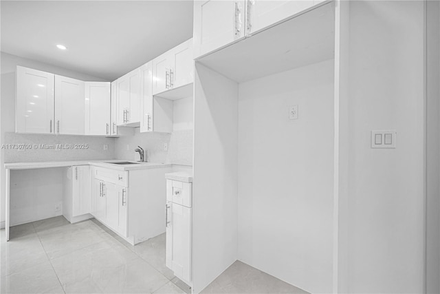 kitchen featuring tasteful backsplash, sink, and white cabinets