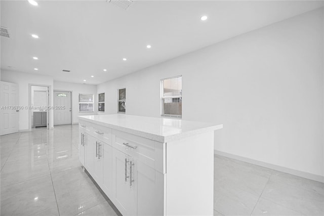 kitchen featuring light stone countertops, white cabinets, and a kitchen island