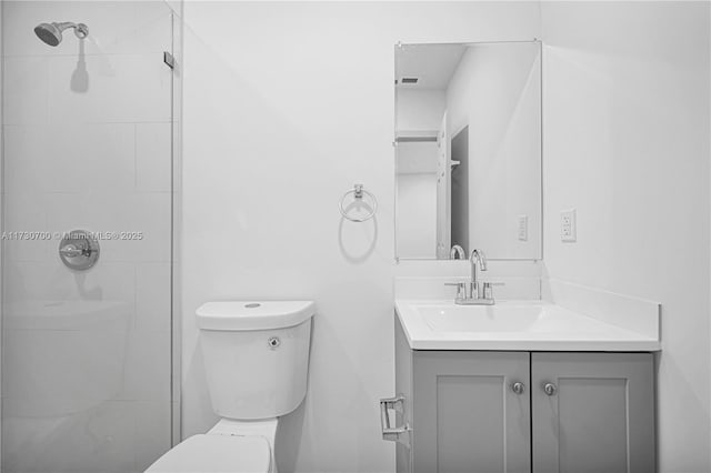 bathroom featuring vanity, toilet, and a tile shower