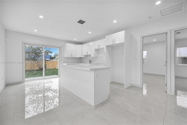 kitchen featuring decorative backsplash, sink, a kitchen island, and white cabinets