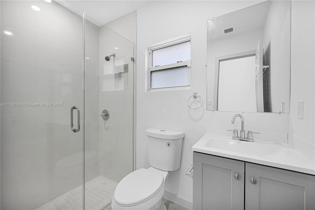 bathroom featuring vanity, toilet, and a shower with shower door