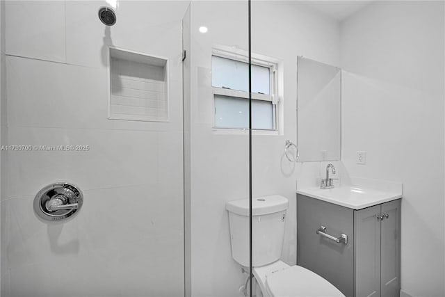 bathroom featuring vanity, toilet, and a tile shower