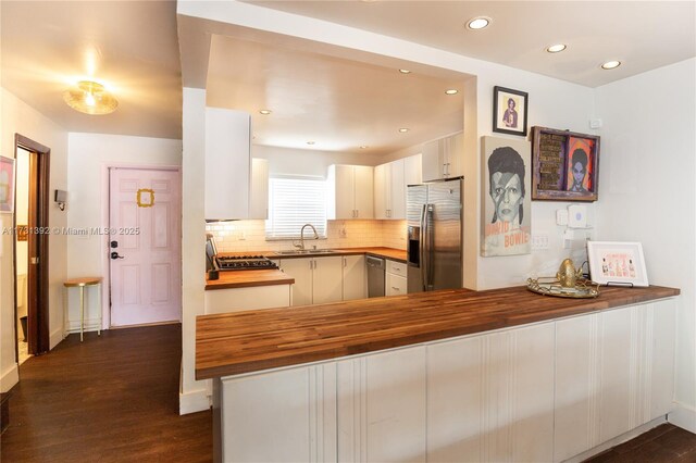 2035 NE 123rd St, North Miami, FL 33181 - kitchen featuring butcher block countertops, appliances with stainless steel finishes, a sink, a peninsula, and dark wood-style floors