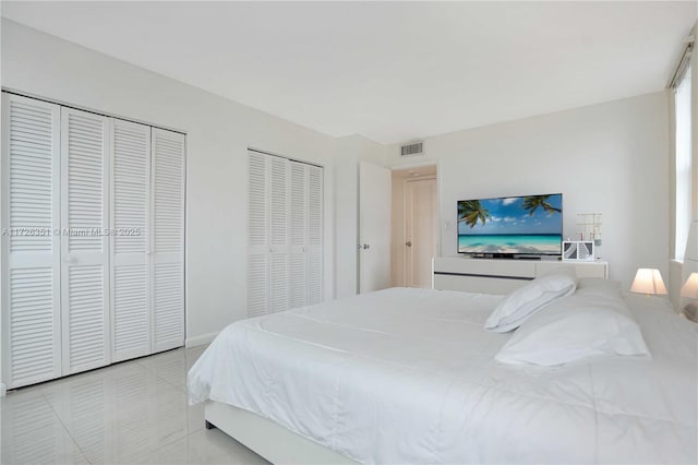 bedroom with light tile patterned floors and two closets