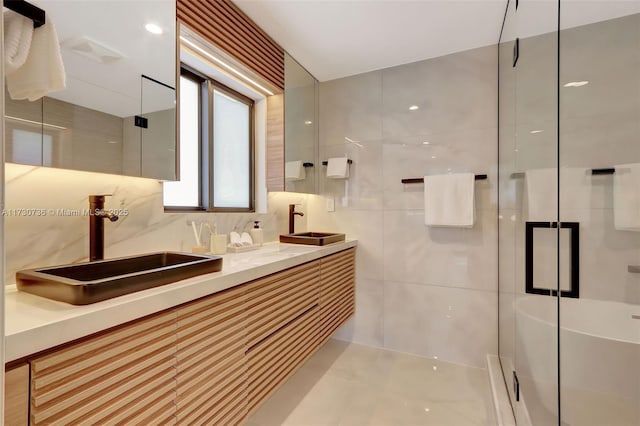 bathroom with tile walls, vanity, tasteful backsplash, and a shower with door