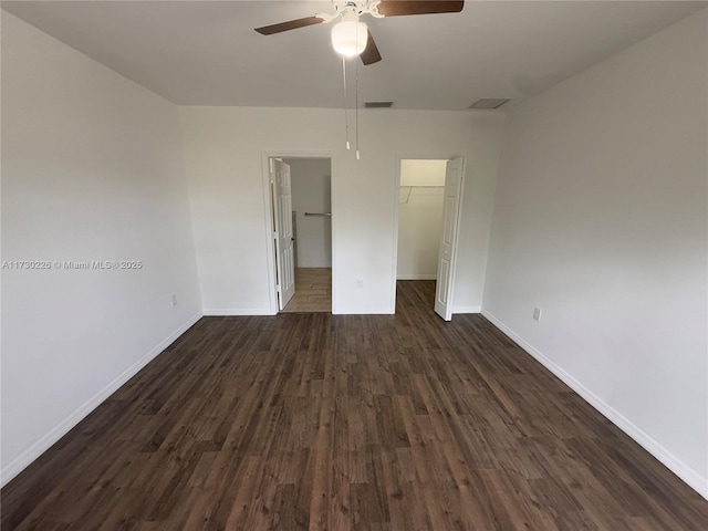 unfurnished bedroom featuring ceiling fan, a walk in closet, dark hardwood / wood-style flooring, and a closet