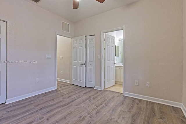 unfurnished bedroom featuring ensuite bathroom, light wood-type flooring, and ceiling fan