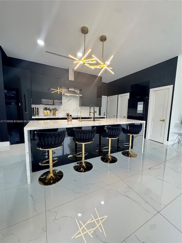 kitchen featuring a large island, hanging light fixtures, tasteful backsplash, a kitchen bar, and wall chimney exhaust hood