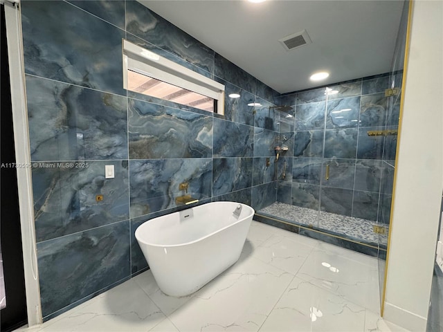 bathroom with shower with separate bathtub and tile walls