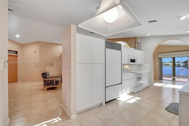 12915 Coral Lakes Dr, Boynton Beach, FL 33437 - kitchen featuring white appliances, light tile patterned floors, white cabinets, arched walkways, and light countertops