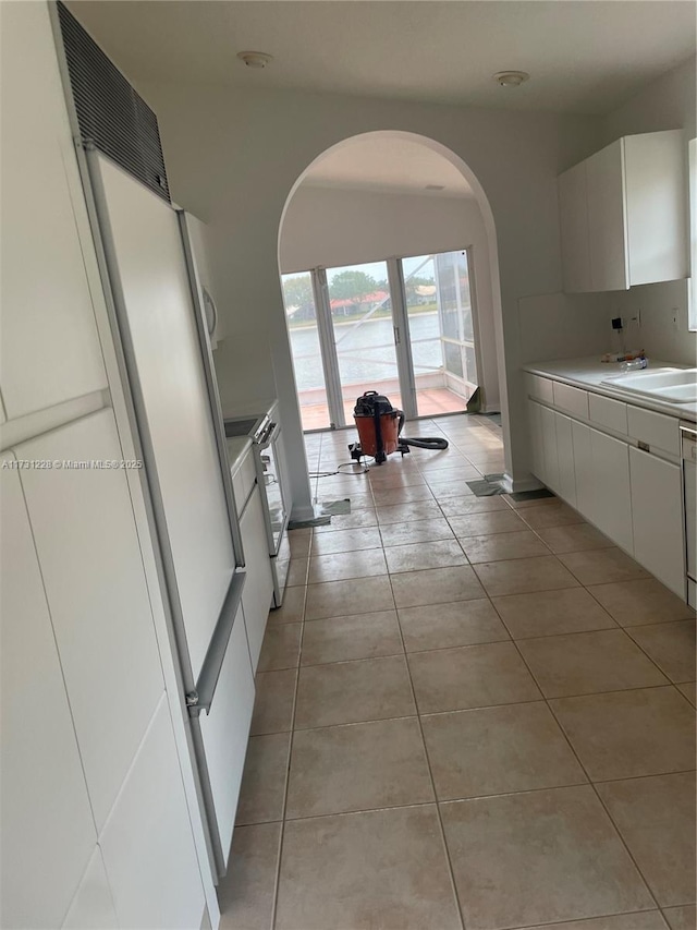 12915 Coral Lakes Dr, Boynton Beach, FL 33437 - kitchen featuring arched walkways, a sink, white cabinetry, light countertops, and light tile patterned floors