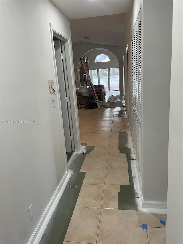 12915 Coral Lakes Dr, Boynton Beach, FL 33437 - hall with arched walkways, tile patterned floors, vaulted ceiling, and baseboards