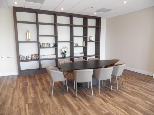 dining space featuring hardwood / wood-style floors, built in features, and a drop ceiling