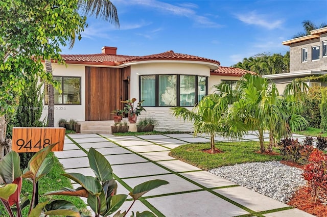 exterior space featuring a tiled roof, a chimney, and stucco siding