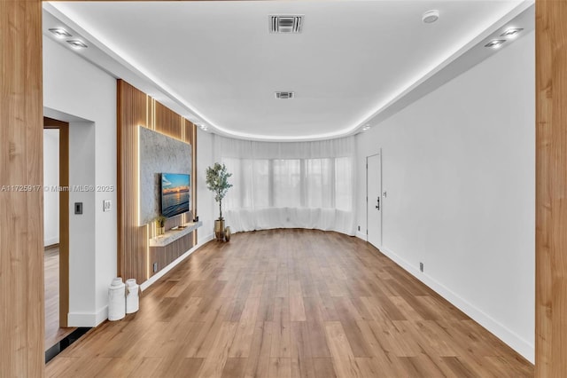 unfurnished living room featuring light wood-type flooring, visible vents, and baseboards