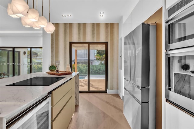 kitchen featuring light wood-style flooring, modern cabinets, appliances with stainless steel finishes, decorative light fixtures, and light stone countertops