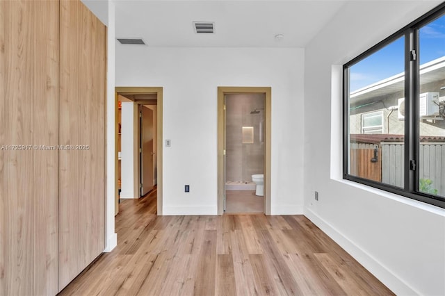 unfurnished bedroom with baseboards, ensuite bath, visible vents, and light wood-style floors