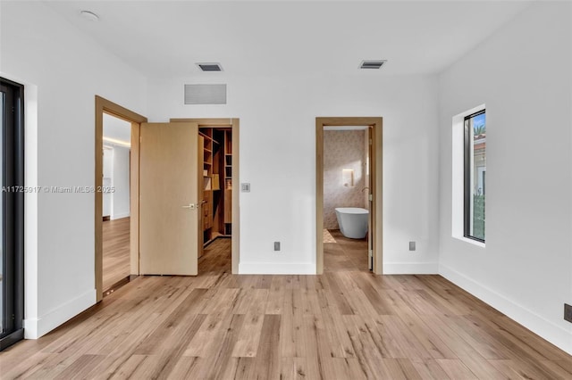 unfurnished bedroom featuring light wood-style floors, visible vents, and a walk in closet