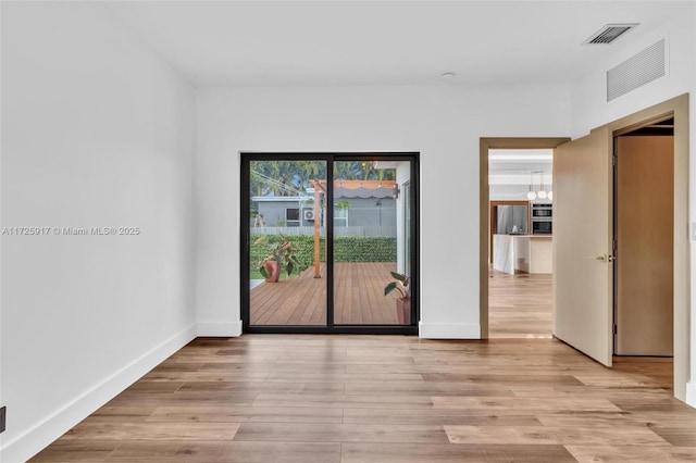 spare room with light wood-style flooring, visible vents, and baseboards