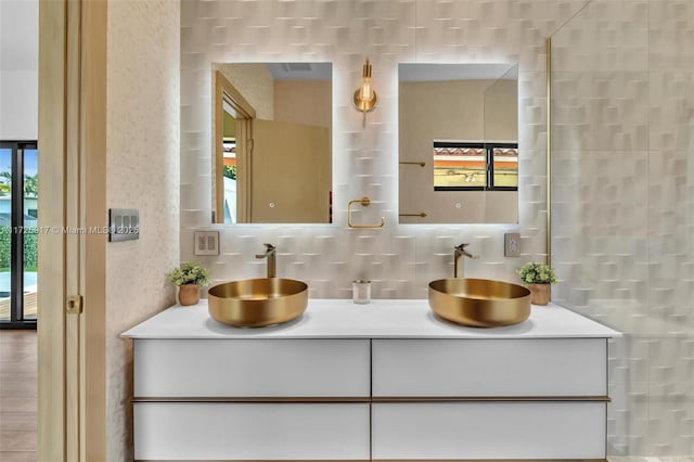 full bathroom with tile walls, a sink, backsplash, and double vanity