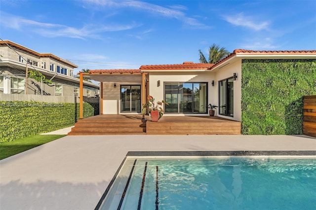 back of property featuring a tile roof, fence, a fenced in pool, and stucco siding