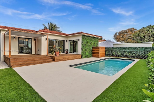 rear view of property with a fenced in pool, a patio, a tiled roof, fence, and stucco siding