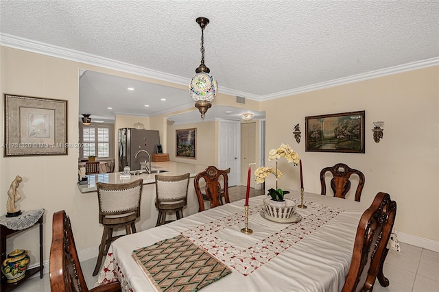 dining room with crown molding, sink, light tile patterned flooring, and a textured ceiling