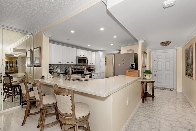 kitchen featuring sink, a breakfast bar area, white cabinetry, appliances with stainless steel finishes, and kitchen peninsula