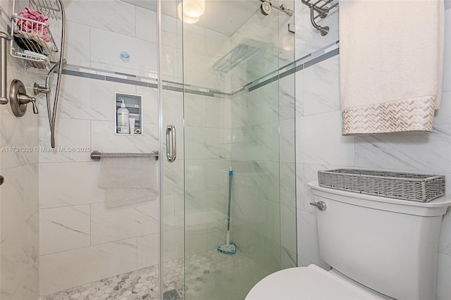 bathroom featuring a shower with shower door and toilet