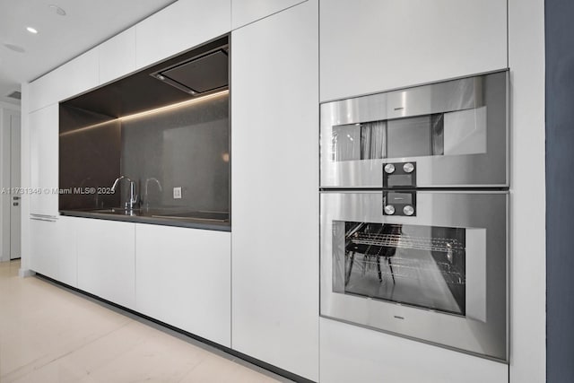 kitchen featuring tasteful backsplash, stainless steel double oven, and white cabinets